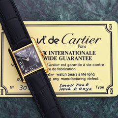 A Cartier Must Tank featuring a rare black Roman numeral dial and a lifetime warranty.